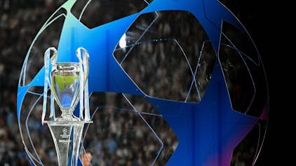 Die Champions League Trophäe steht auf einem Podest. Im Hintergrund ist ein großes blaues Gebilde in Form des Champions League-Balles zu erkennen.