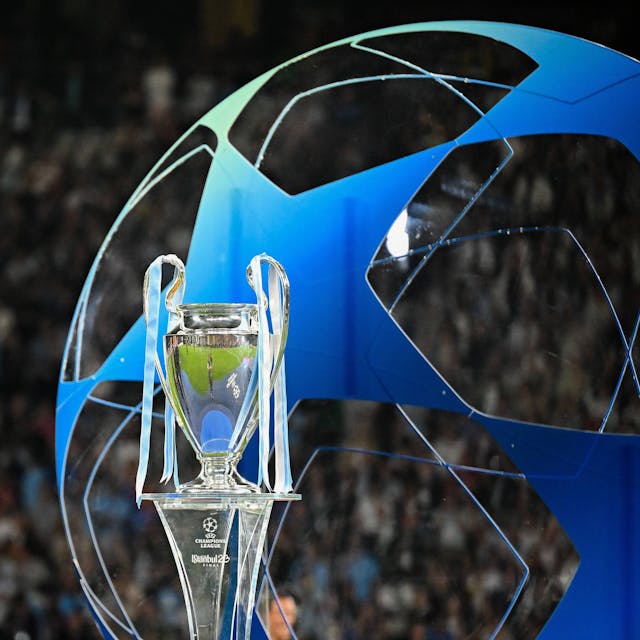 Die Champions League Trophäe steht auf einem Podest. Im Hintergrund ist ein großes blaues Gebilde in Form des Champions League-Balles zu erkennen.
