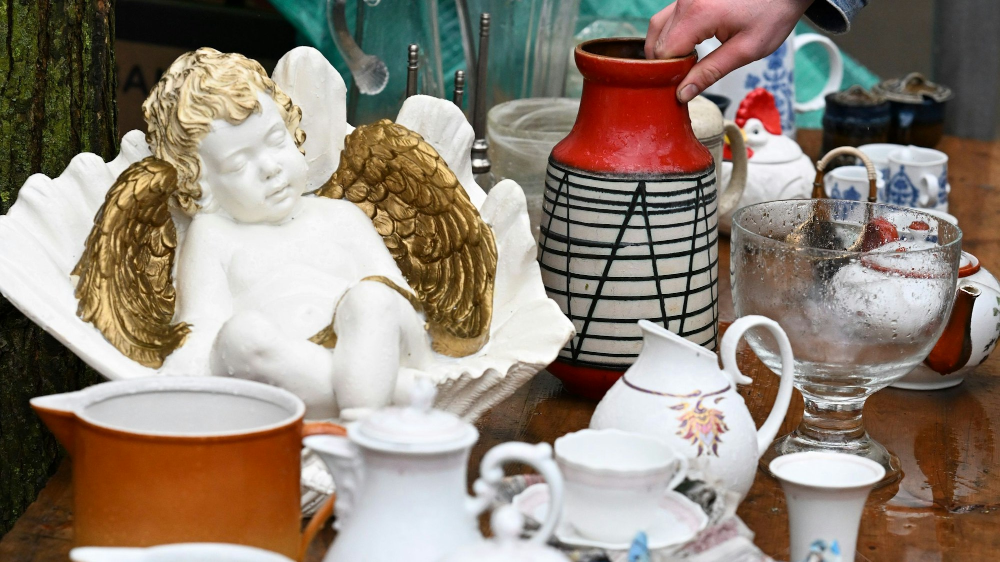 Eine Vase steht zwischen unterschiedlichen Dingen aus Keramik auf einem Flohmarkt.
