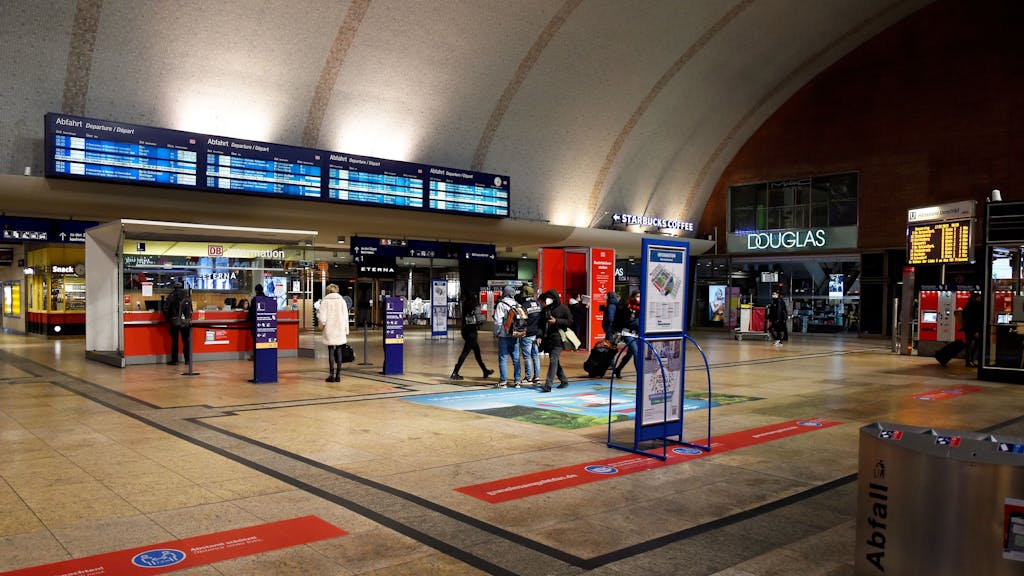 Menschen stehen am Kölner Hauptbahnhof an der Schlange vor dem zentralen Info-Point.