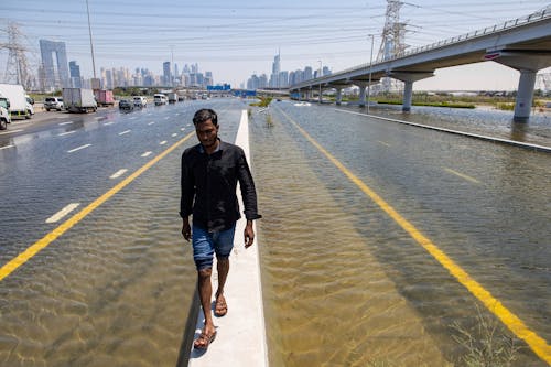 18.04.2024, Vereinigte Arabische Emirate, Dubai: Ein Mann geht entlang einer Straßensperre auf der Sheikh Zayed Road inmitten von Hochwasser, das durch starken Regen verursacht wurde. In den Vereinigten Arabischen Emiraten kam es nach schweren Regenfällen zu Überschwemmumngen.