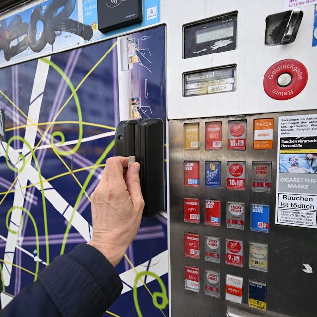 Ein Mann zieht seinen Ausweis durch den Schlitz eines Zigarettenautomaten. Ein solcher ist in Köln-Vingst gesprengt worden. (Symbolbild)