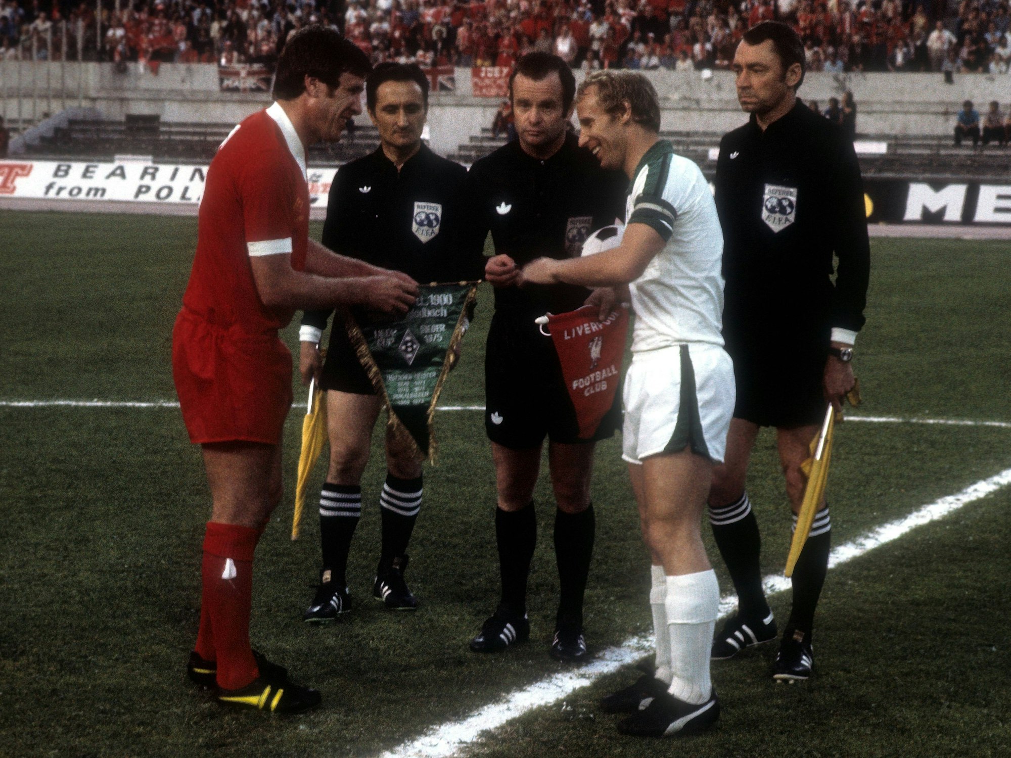 Emlyn Hughes (FC Liverpool) und Berti Vogts (Borussia Mönchengladbach) vor Schiedsrichter Robert Wurtz (Frankreich) bei der Seitenwahl.