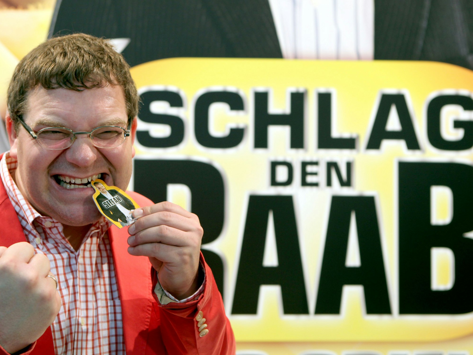 TV-Moderator Elton präsentiert auf eine Raab-Pappfigur beißend in Nürnberg (Mittelfranken) während der Neuheitenschau zur Spielwarenmesse das Spiel zur Fernsehsendung „Schlag den Raab“ von Ravensburger, hier im Februar 2010.