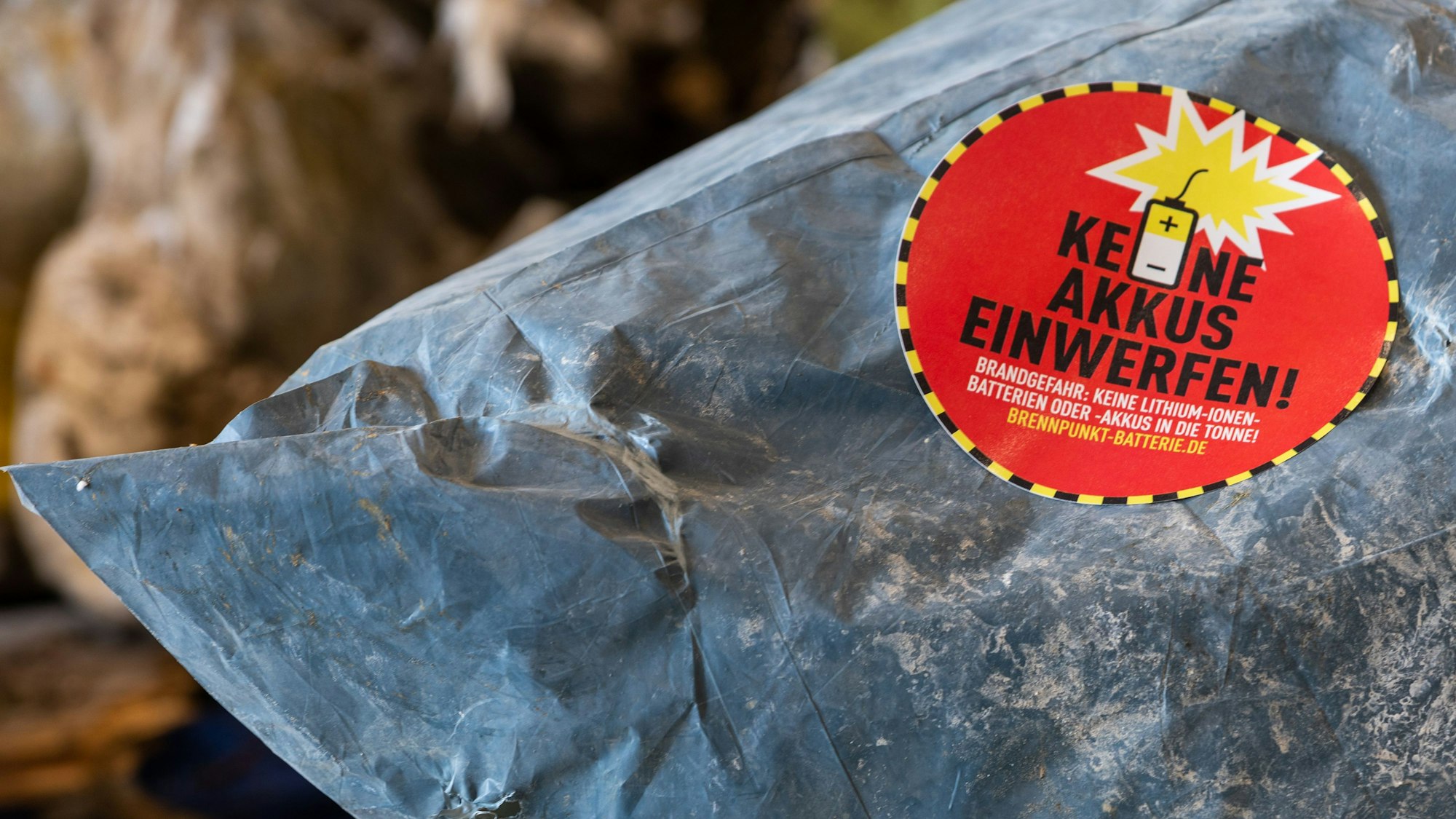 Ein Aufkleber mit der Aufschrift „Keine Akkus einwerfen“ klebt auf einem Müllsack
