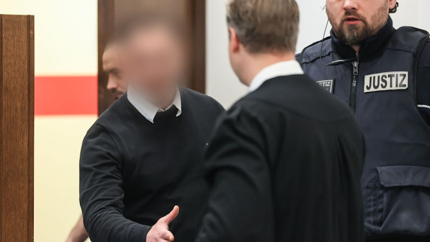 Der 27-jährige Angeklagte begrüßt seinen Verteidiger beim Prozessauftakt im Landgericht Köln.