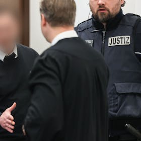 Der 27-jährige Angeklagte begrüßt seinen Verteidiger beim Prozessauftakt im Landgericht Köln.