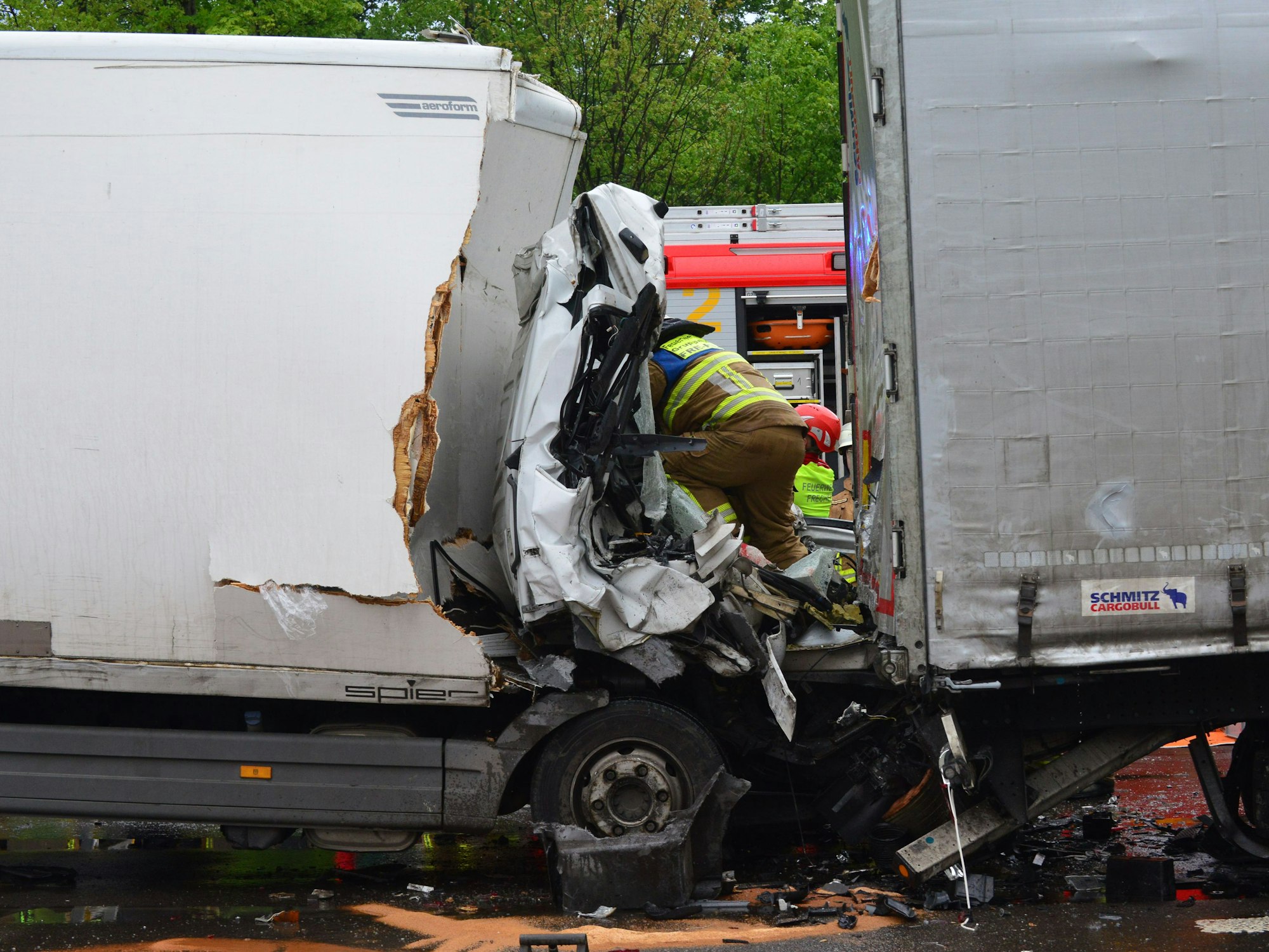 Ein Feuerwehrmann kriecht in eine völlig zerstörte Fahrerkabine eines Kleintransporters.