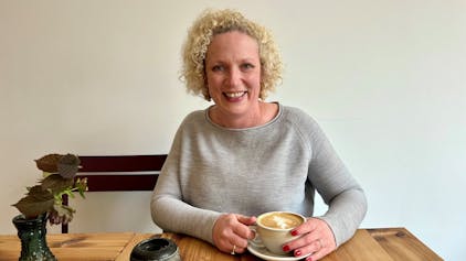 Blonde Frau mit Cappuccino im Café