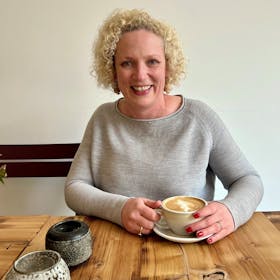 Blonde Frau mit Cappuccino im Café