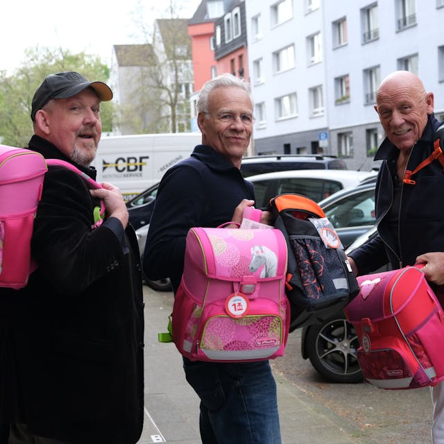 Die Schauspieler Dietmar Bär, Klaus J. Behrendt und Joe Bausch halten vier von insgesamt 774 hochwertigen Schulranzen, die der Kölner „Tatort-Verein“ an arme Kinder spendet, in der Hand.&nbsp;