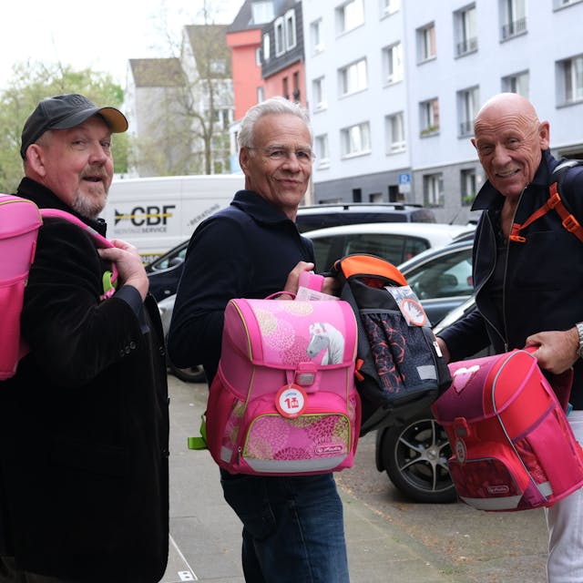 Die Schauspieler Dietmar Bär, Klaus J. Behrendt und Joe Bausch halten vier von insgesamt 774 hochwertigen Schulranzen, die der Kölner „Tatort-Verein“ an arme Kinder spendet, in der Hand.&nbsp;