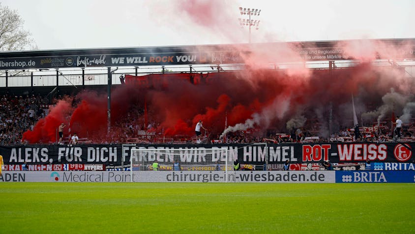 Die Fans von Fortuna Düsseldorf zeigen beim Spiel in Wiesbaden ein Banner für den verstorbenen Mannschaftsbetreuer Aleksandar Spengler.