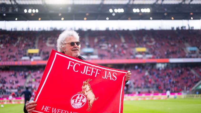 Der Kölner Musiker Wolfgang Niedecken hält vor der Partie eine Fahne des 1. FC Köln in den Händen.