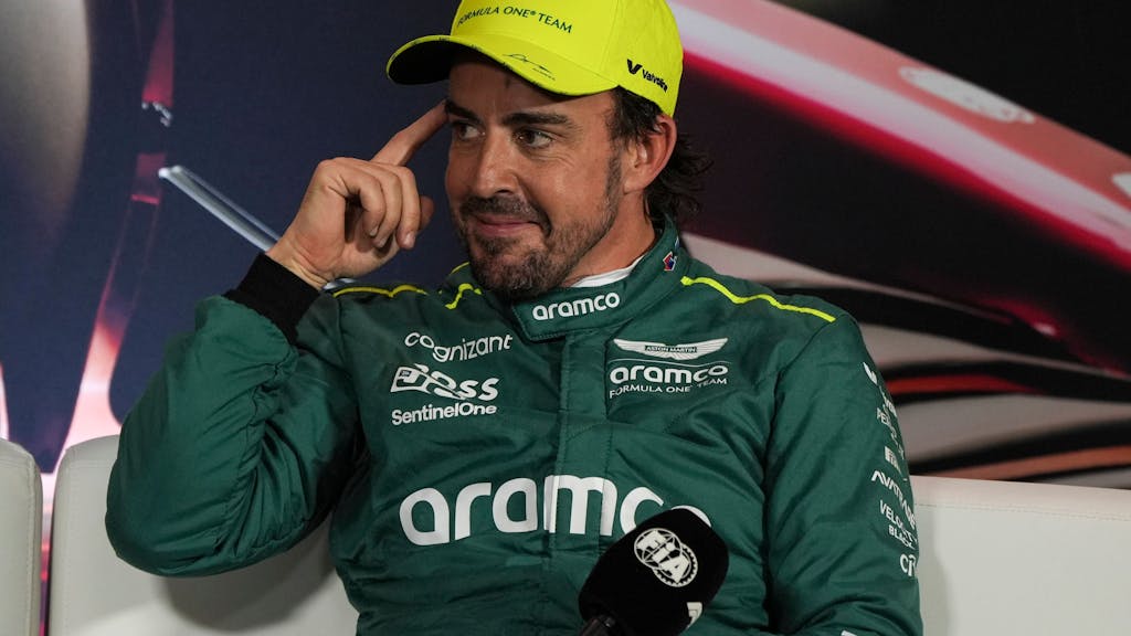 Fernando Alonso lächelt schelmisch bei einer Pressekonferenz der Formel 1.