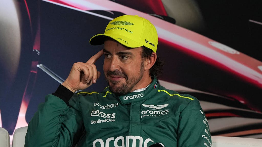 Fernando Alonso lächelt schelmisch bei einer Pressekonferenz der Formel 1.