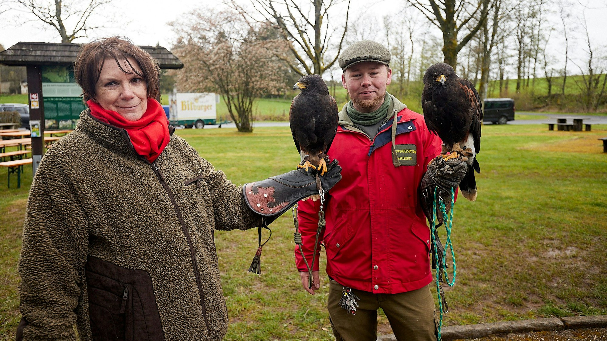 Eine Falknerin und ein Falkner halten jeweils einen Greifvogel auf der ausgestreckten Hand.