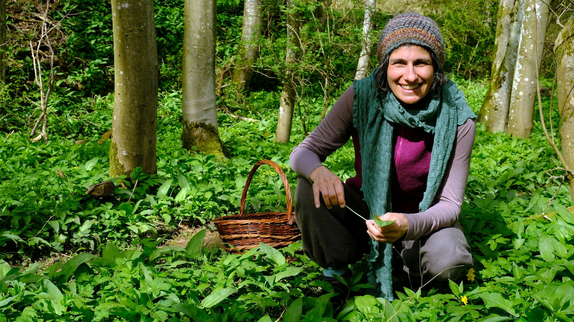 Naturpädagogin Jasmin Khalil kniet inmitten von Bärlauchpflanzen im Wald.