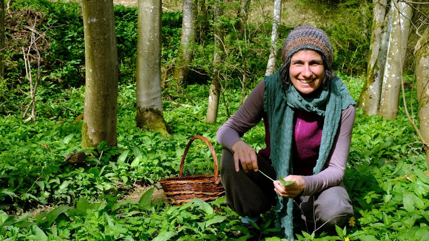 Naturpädagogin Jasmin Khalil kniet inmitten von Bärlauchpflanzen im Wald.