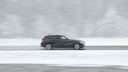 Ein schwarzer Wagen fährt über eine teils schneebedeckte Landesstraße bei Böhmenkirch.&nbsp;