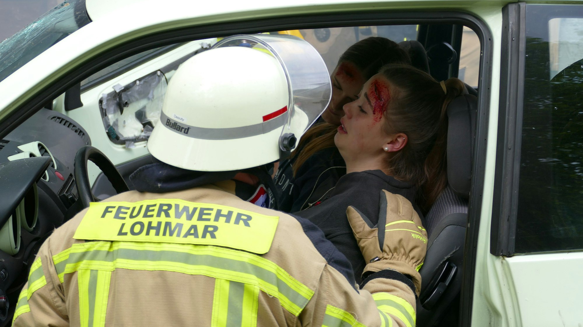 Ein Feuerwehrmann hockt neben einer im Auto sitzenden Verletzten.