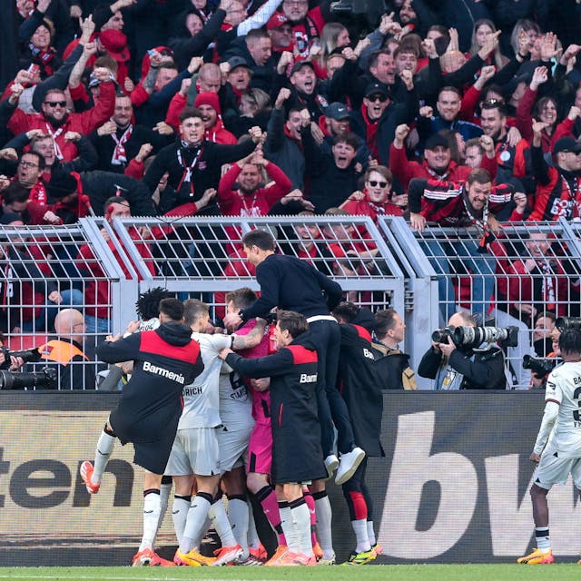 Die Leverkusener bejubeln vor den angereisten Fans den späten Ausgleichstreffer durch Josip Stanisic. Trainer Alonso wirft sich auf die Jubeltraube.