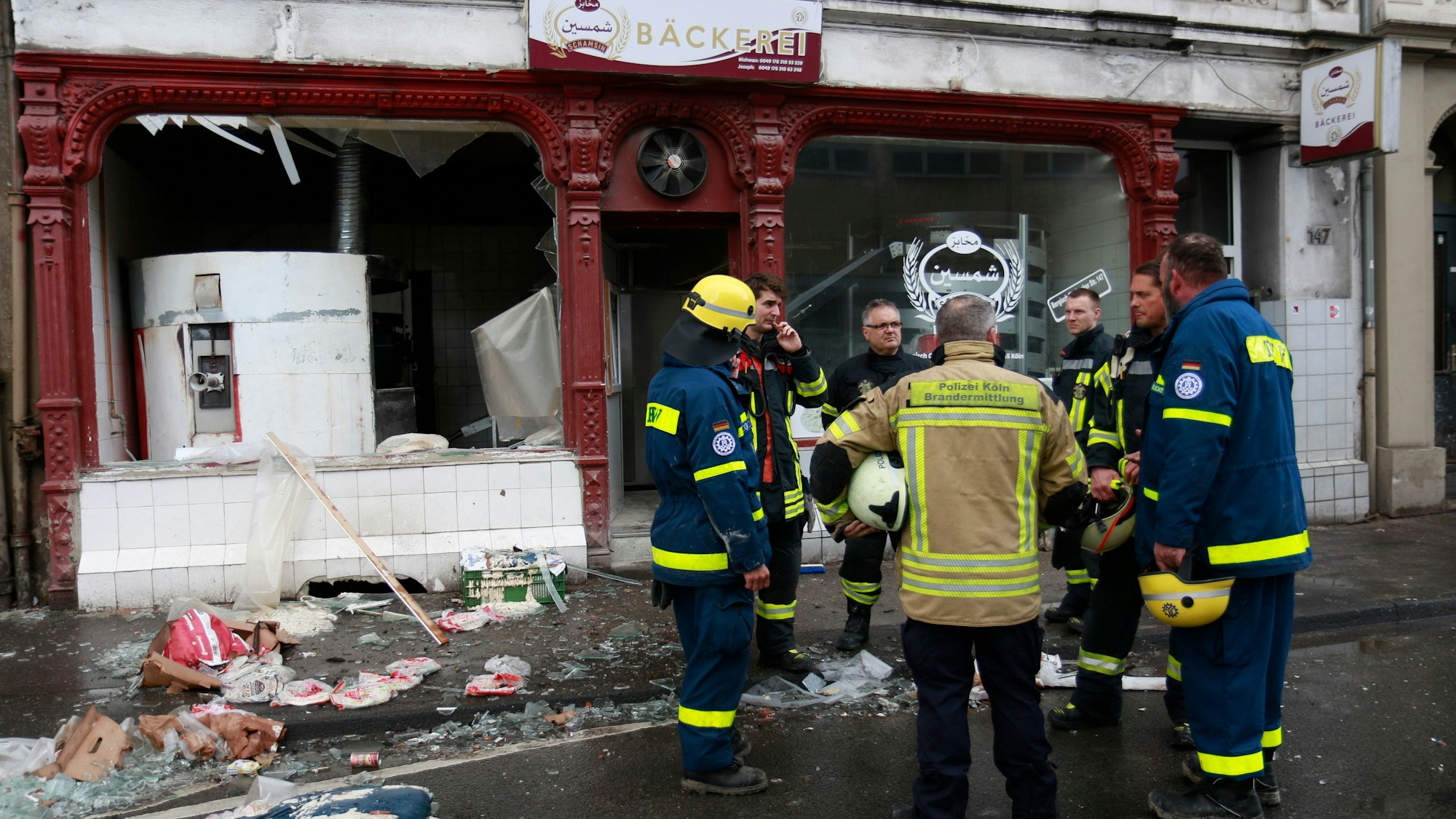 Brandermittler und Feuerwehleute stehen vor einer Bäckerei, die durch die Verpuffung zerstört wurde.