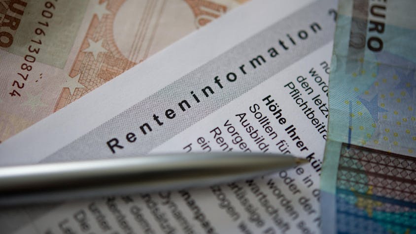 Ein Kugelschreiber und ein Geldschein liegen auf einer Renteninformation, dem jährlichen Schreiben der Deutschen Rentenversicherung an alle Versicherten zu ihrer gesetzlichen Rente.