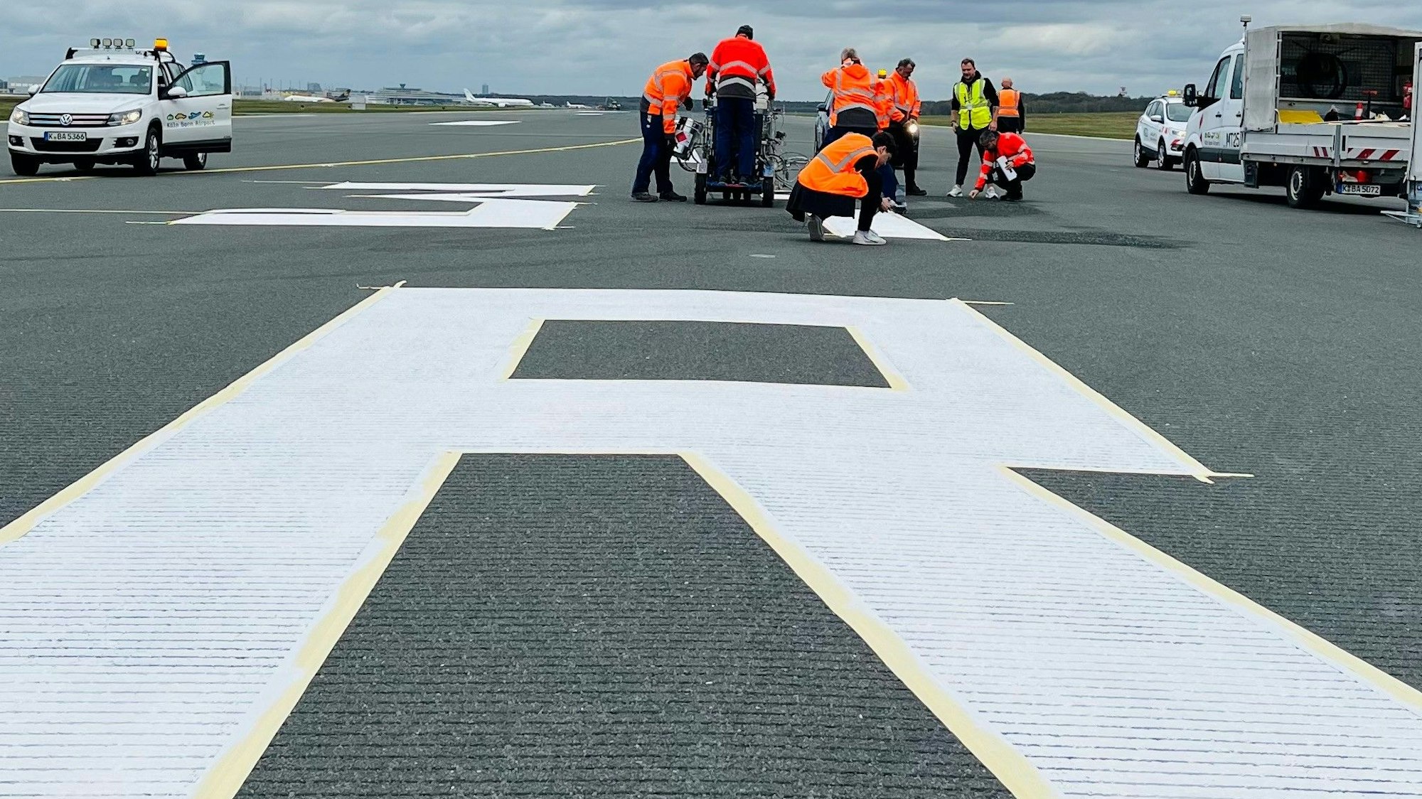 Arbeiter bringen die neuen Markierungen auf der Start- und Landebahn auf dem Flughafen Köln/Bonn an.
