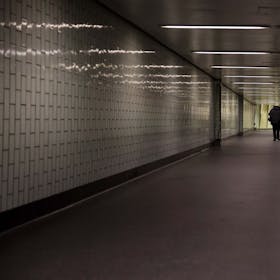 Eine Person geht durch einen langen Tunnel, der nicht hell beleuchtet ist.