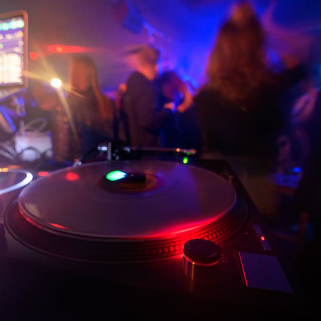 Partygänger tanzen vor einem DJ-Pult.