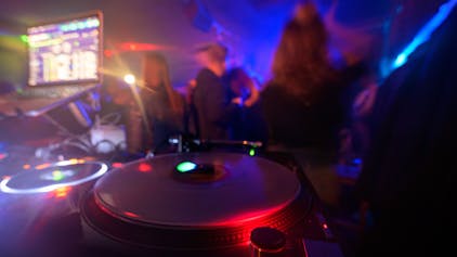 Partygänger tanzen vor einem DJ-Pult.