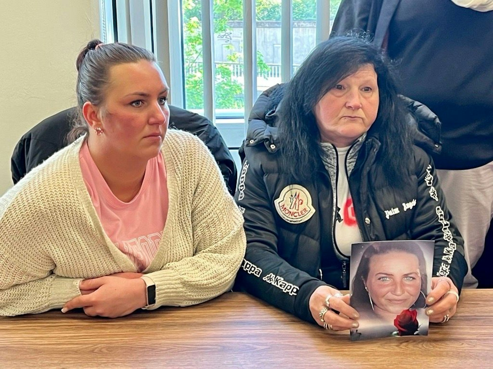 Zwei Frauen sitzen im Gerichtssaal und zeigen ein Bild.
