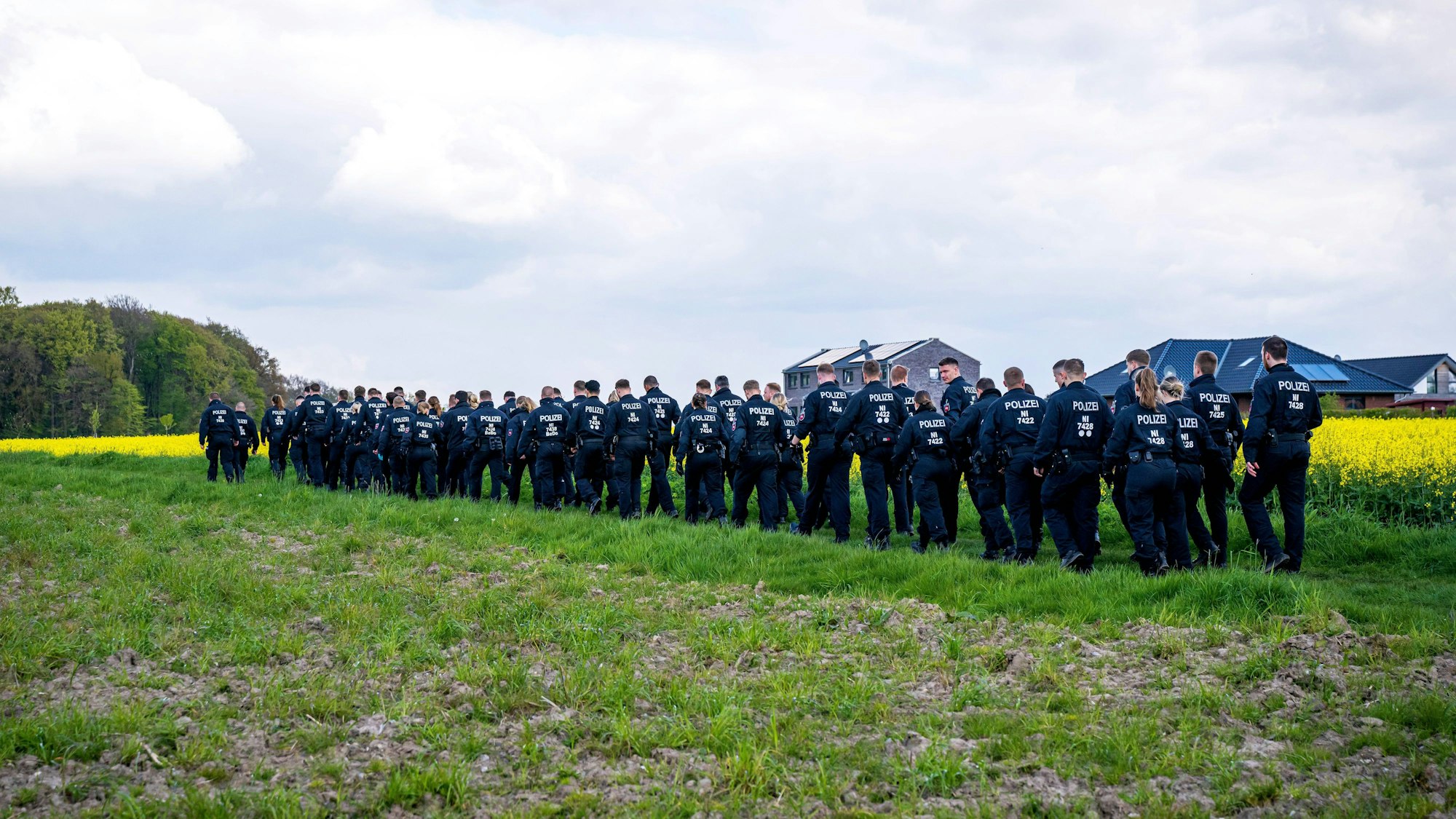 Polizisten laufen über einen Feldweg auf den Wald zu. In Bremervörde suchen zahlreiche Einsatzkräfte nach einem vermissten Sechsjährigen.