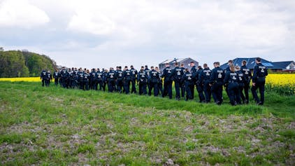 Polizisten laufen über einen Feldweg auf den Wald zu. In Bremervörde suchen zahlreiche Einsatzkräfte nach einem vermissten Sechsjährigen.