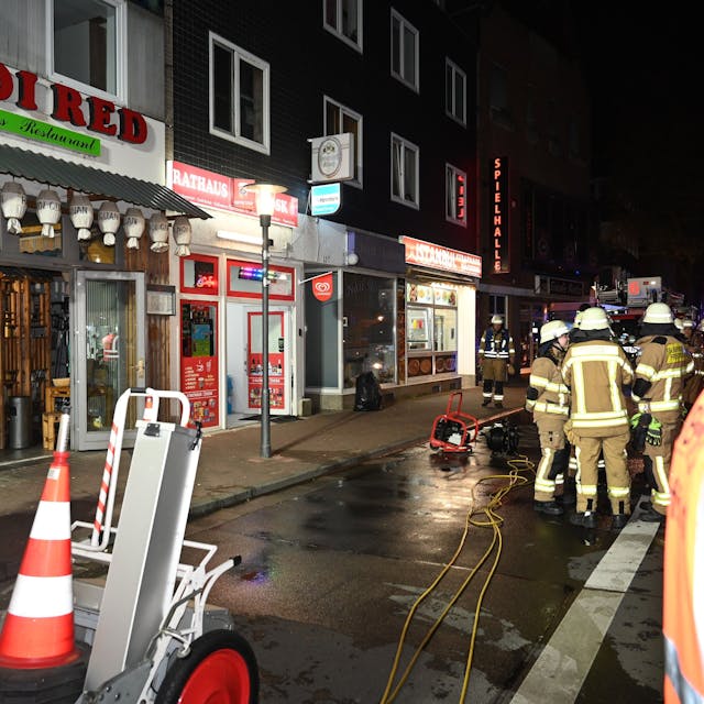 Die Einsatzkräfte der Feuerwehr vor einem Laden auf der Hauptstraße in Frechen.