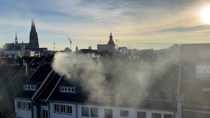 Dichter Rauch, der über den Dächern des Eigelsteinviertels in der Innenstadt steht.