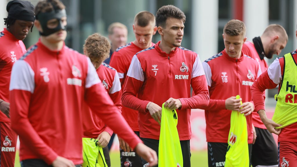 Die FC-Profis ziehen sich beim Training am Geißbockheim Leibchen an.