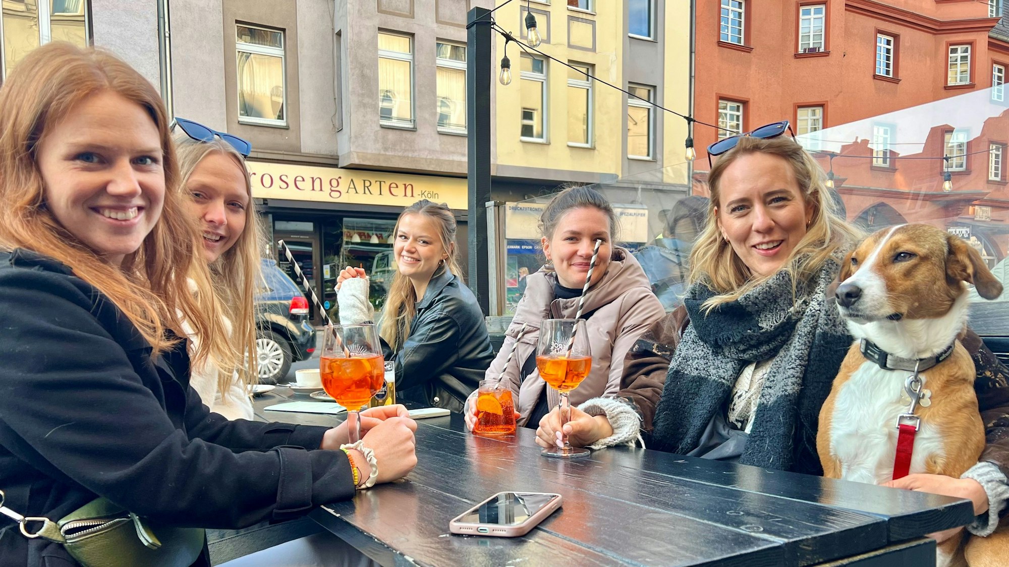 Fünf junge Frauen im Straßenlokal trinken Aperol