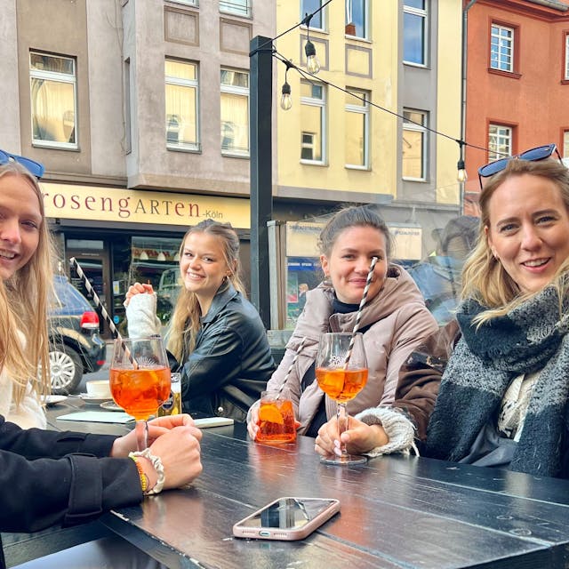 Fünf junge Frauen im Straßenlokal trinken Aperol