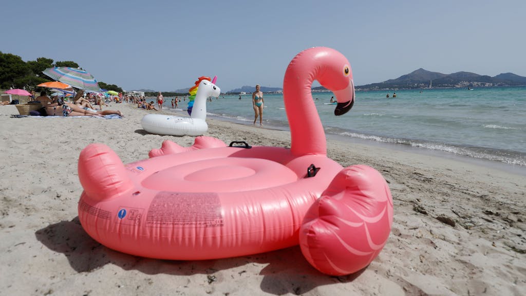 Ein aufblasbarer rosa Flamingo liegt am Strand von Playa de Muro im Norden von Mallorca.