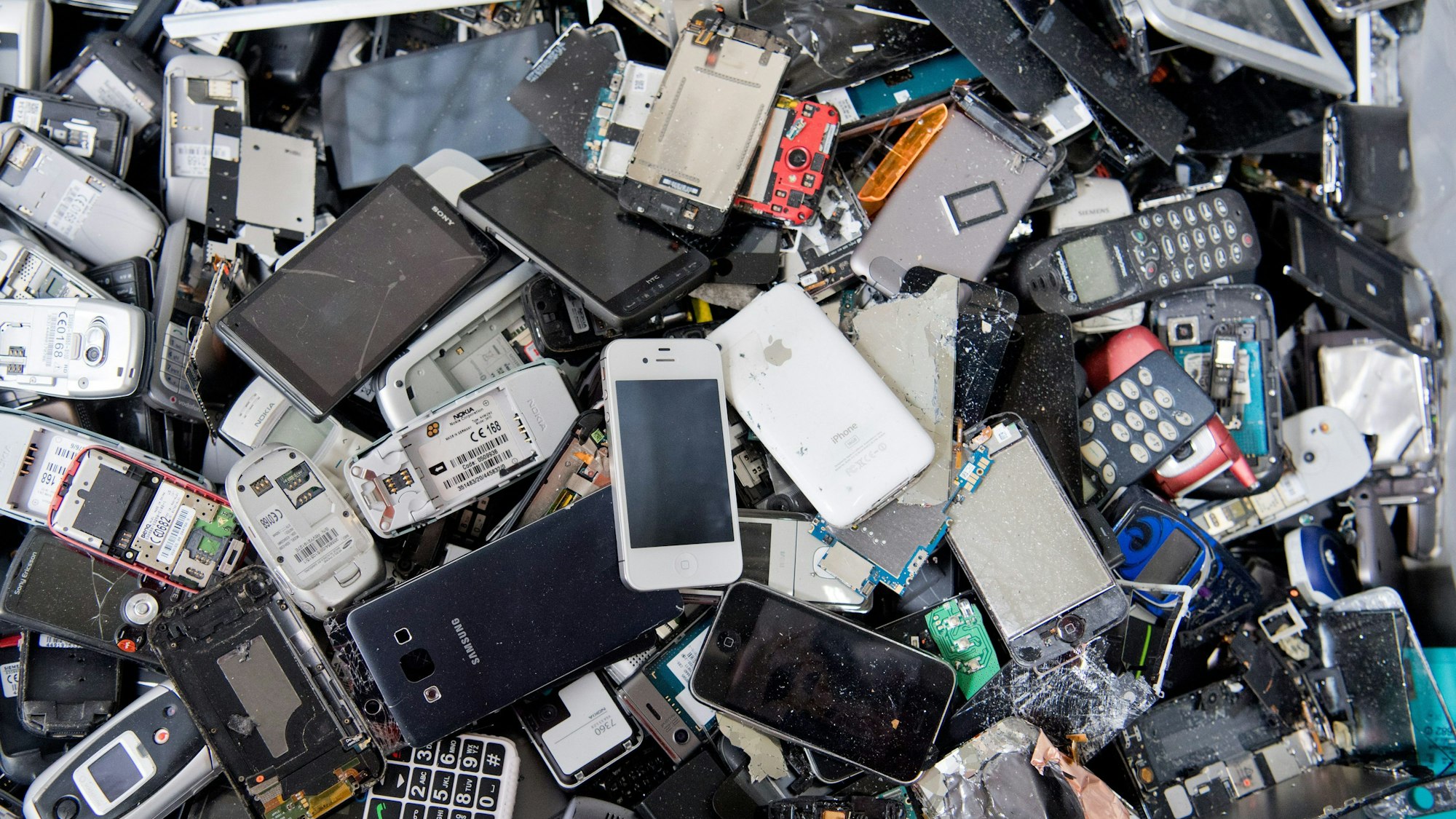 ARCHIV - 19.07.2016, Niedersachsen, Goslar: Alte Handys und Smartphones liegen in einem Container, ehe sie geschreddert werden.