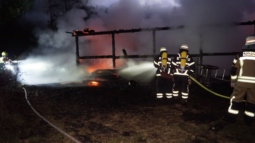 Das Bild zeigt, wie Feuerwehrleute die Flammen mit Wasser bekämpfen.