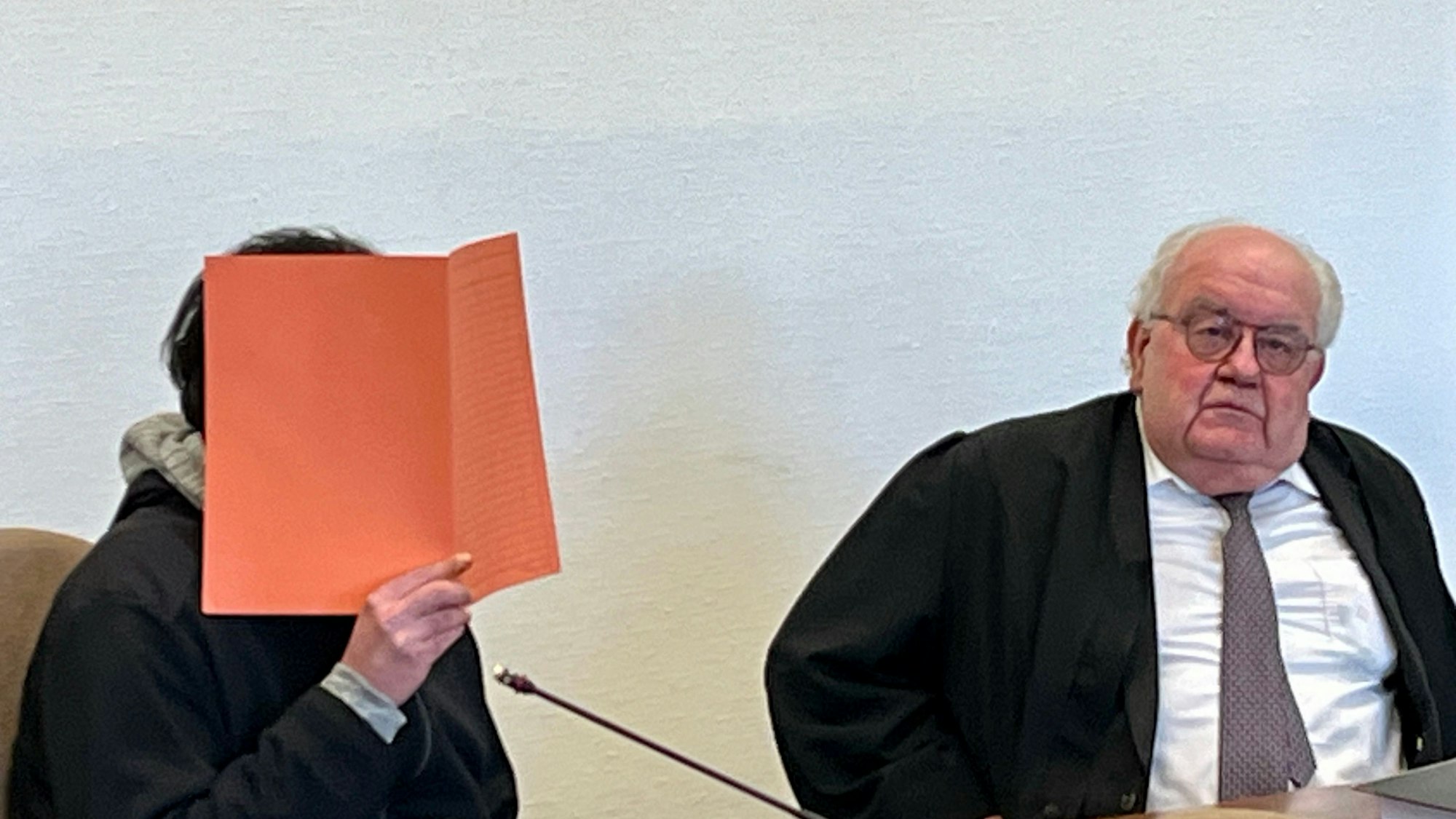 Der des Mordes angeklagte 34 Jahre alte Rheindorfer sitzt, hinter einem Aktendeckel versteckt, neben seinem Anwalt Gottfried Reims.