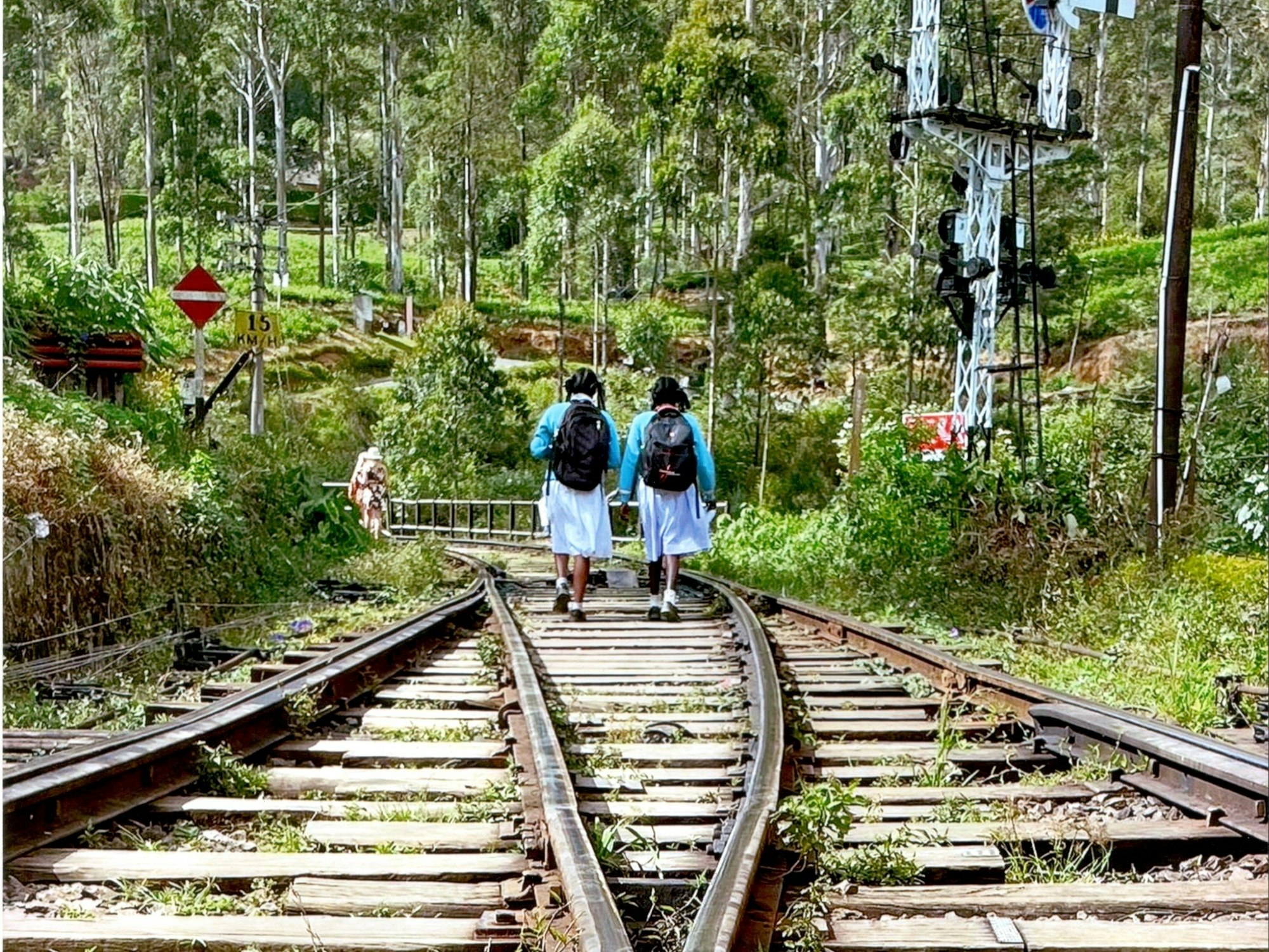 Zwei Frauen laufen in Sri Lanka auf alten Bahnschienen entlang.