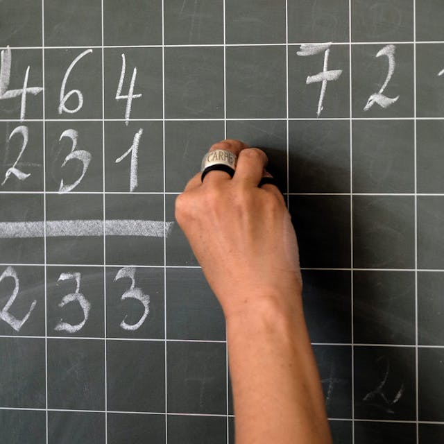 Eine Lehrerin schreibt Mathematikaufgaben auf eine Schultafel.&nbsp;