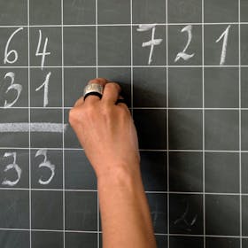 Eine Lehrerin schreibt Mathematikaufgaben auf eine Schultafel.&nbsp;