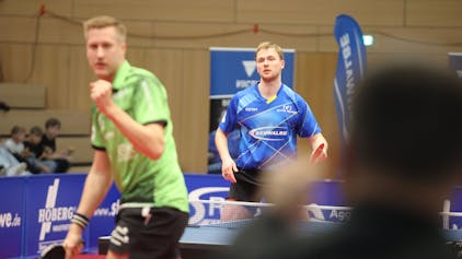 Der Bremer Mattias Falck reckt im Vordergrund die Siegerfaust, während im Hintergrund ein frustrierter Benedikt Duda zu sehen ist.