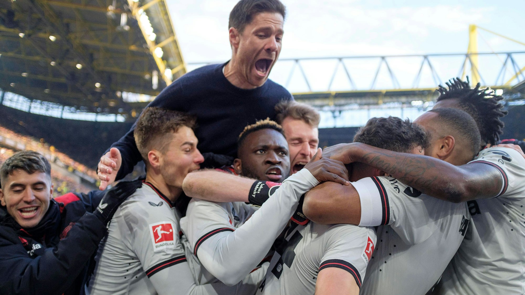 Victor Boniface bejubelt mit seinen Kollegen und Trainer Xabi Alonso das Tor von Josip Stanisic in Dortmund zum 1:1, das die Leverkusener Serie von Spielen ohne Niederlage rettete.