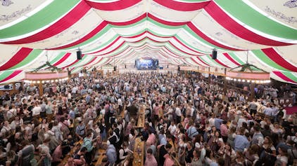 Besucher und Besucherinnen feiern in einem Festzelt des Stuttgarter Frühlingsfestes.